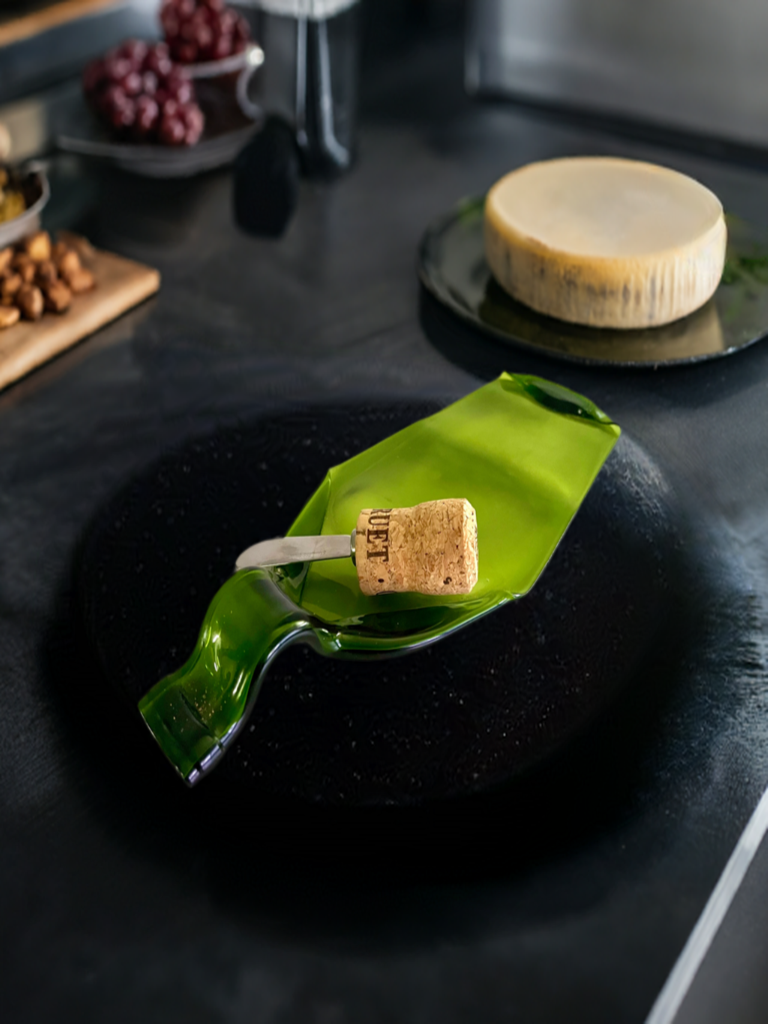 Eco-friendly wine bottle cheese board displayed with a selection of cheeses and nuts, featuring a wine cork spreader knife for serving.