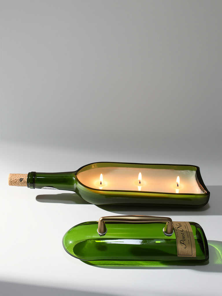 Green glass bottle repurposed as a candle holder with three lit candles inside.