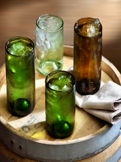 A set of 4 drinking glasses of two green, one clear, and one brown.